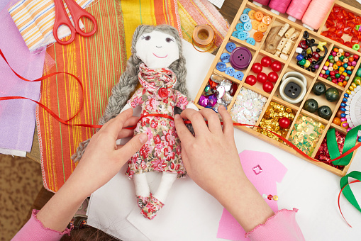 girl sews doll clothes, top view, sewing accessories top view, seamstress workplace, many object for needlework, handmade and handicraft