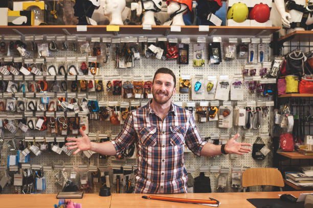 Portrait of sales person in sports and outdoor equipment store while standing behind the cash register and smiling.