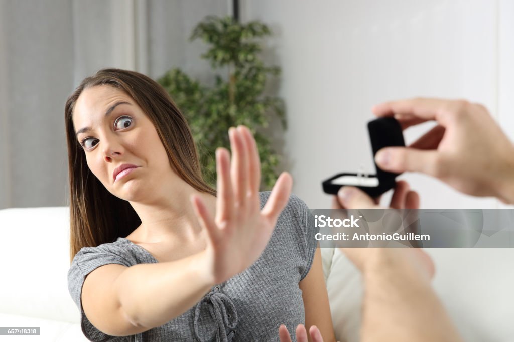 Girlfriend rejecting a marriage proposal Scared girlfriend rejecting a marriage proposal at home. Humorous situation Engagement Stock Photo