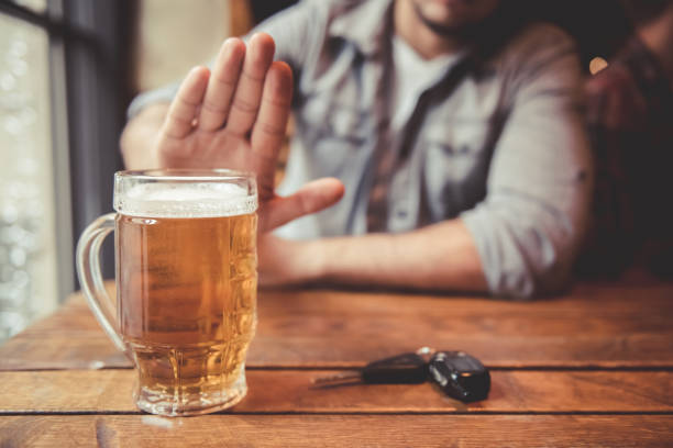 Guy at the pub Do not drink and drive! Cropped image of man showing stop gesture and refusing to drink beer. Car keys lying near drink stock pictures, royalty-free photos & images