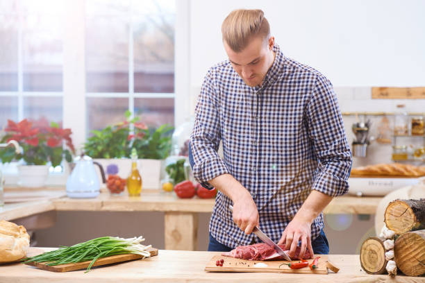 istock Handsome man cooking at home preparing meat stake from pork or beef or lamb 657428896