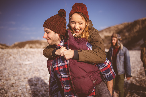 Close up of young woman getting a piggyback ride from boyfriend on winter island vacation