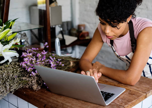 mujer usando laptop online flower shop - florist small business flower shop owner fotografías e imágenes de stock