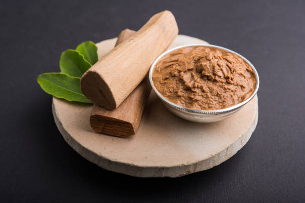 ayurvedic chandan powder or sandalwood paste in silver bowl with sticks and leaves placed over sahan or sahana or circular stone base for creating paste - cold tint imagens e fotografias de stock