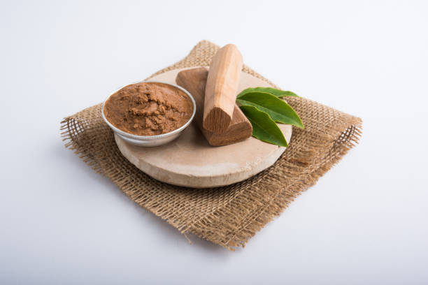 ayurvedic chandan powder or sandalwood paste in silver bowl with sticks and leaves placed over sahan or sahana or circular stone base for creating paste - cold tint imagens e fotografias de stock