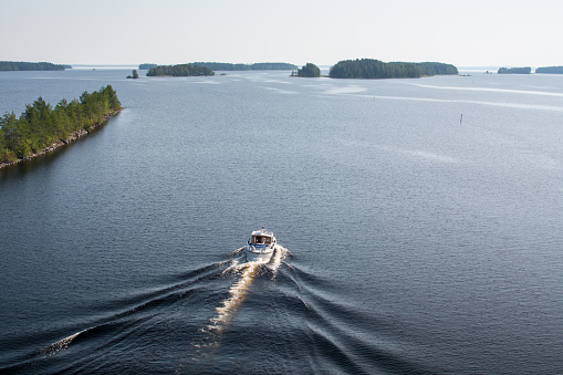 Landscape of Saimaa lake, ship and wake wave on calm water from above, Finland\