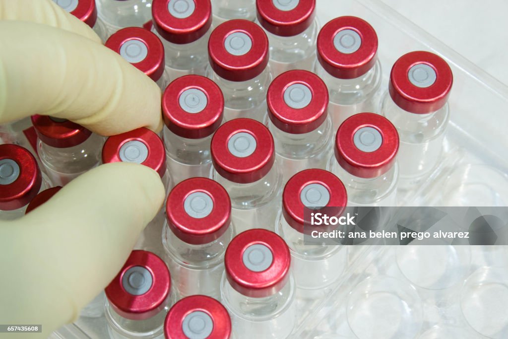 Hand taking a medicine bottle in the laboratory Hand with surgery gloves taking a medicine bottle in the laboratory Healthcare And Medicine Stock Photo