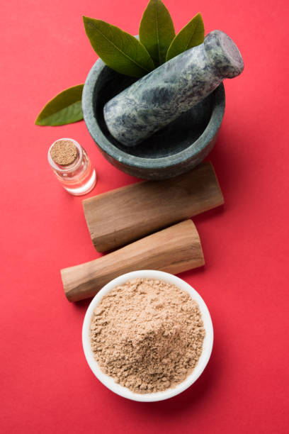 Chandan or sandalwood powder with traditional mortar, sandalwood sticks, perfume or oil and green leaves. selective focus stock photo