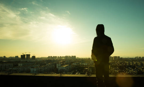istock Young man looking city sunset,standing on top of roof 657449622