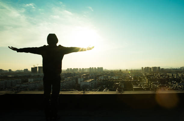 istock Young man standing on roof with arm raising 657449660