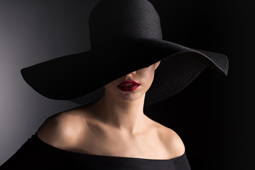 young woman in black hat with red lips on black
