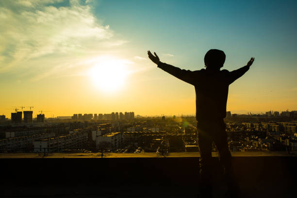 istock Young man standing on roof with arm raising 657449876