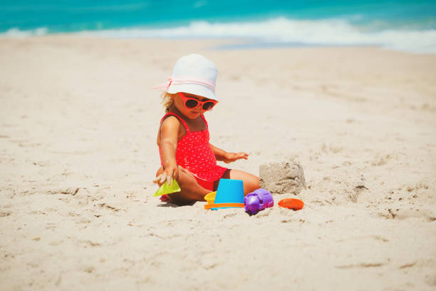 istock cute little girl play with sand on beach 657457452
