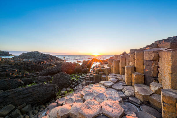 turista al tramonto su giants causeway, irlanda del nord - causeway foto e immagini stock