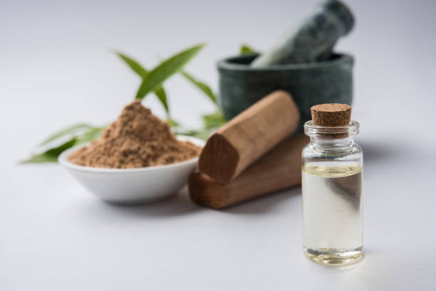 chandan or sandalwood powder with traditional mortar, sandalwood sticks, perfume or oil and green leaves. selective focus - cold tint imagens e fotografias de stock