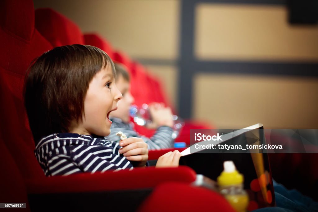 Two preschool children, twin brothers, watching movie in the cinema, eating popcorn Movie Theater Stock Photo
