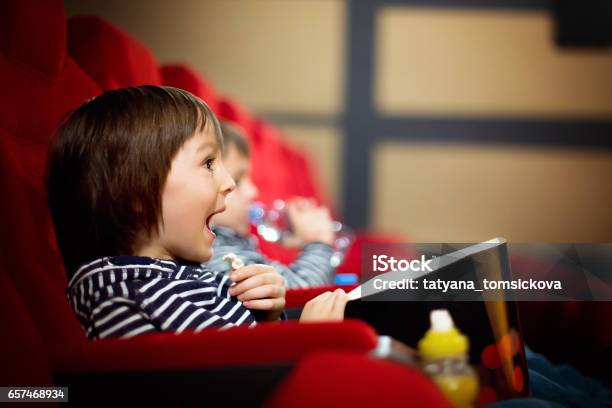 Two Preschool Children Twin Brothers Watching Movie In The Cinema Eating Popcorn Stock Photo - Download Image Now