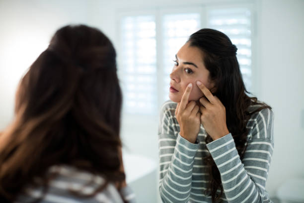 istock Woman squeezing pimples in front of bathroom mirror 657486114