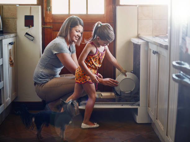 Getting her to help with the chores from a young age Shot of a mother and her little daughter using a dishwashing machine at home dog dishwasher stock pictures, royalty-free photos & images