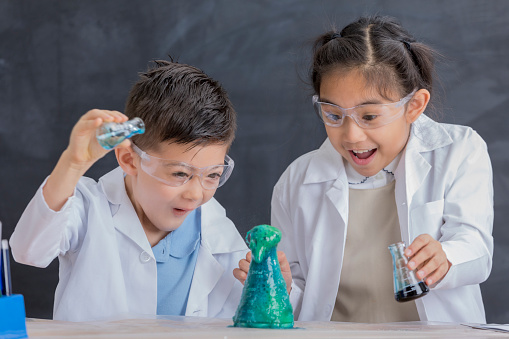 Elementary STEM school kids watch chemical reaction during experiment.