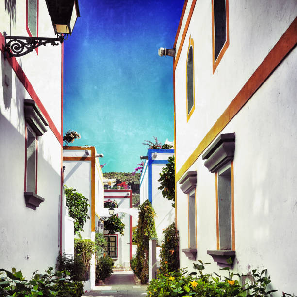 Street with white houses colonia shown in Puerto de Mogan, Spain.  Favorite vacation place for tourists and locals on island. Filtered