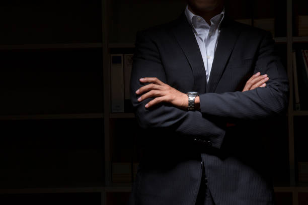 businesspeople arm in arm in the darkness - businessman business arms crossed business person imagens e fotografias de stock