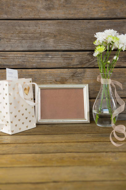 istock Gift bag, photo frame and flower vase on wooden surface 657535964