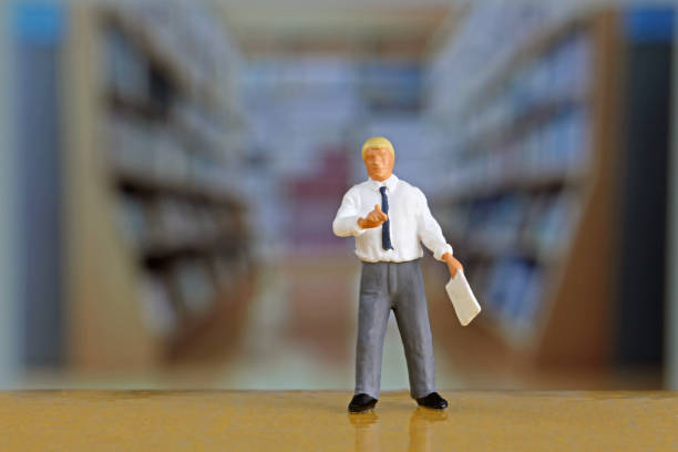 istock Businessmen in miniature in the library 657543262