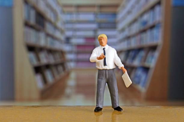 istock Businessmen in miniature in the library 657543272