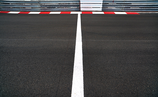 Start and Finish motor race line asphalt on Grand Prix street circuit. Red and white curb, guard rail or guardrail on background
