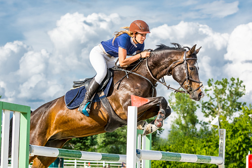 Jockey on her horse leaping over a hurdle, jumping over hurdle on competition