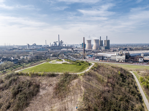 DUISBURG / GERMANY - OCTOBER 06 2016 : Landmark Tiger and Turtle standing on a hill while HKM is producing steel in the background, aerial