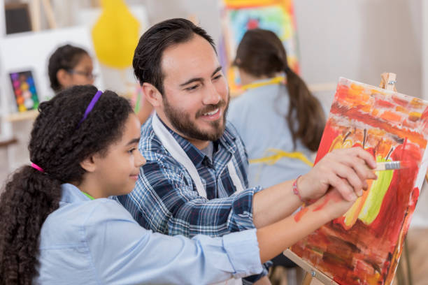istock Confident Hispanic art teacher works with young student 657565308