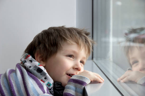 istock Dreamy boy looks out window 657565750