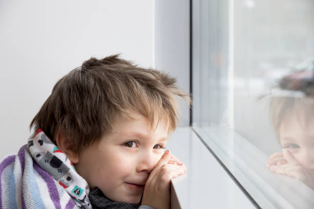 istock Dreamy boy looks out window 657565834