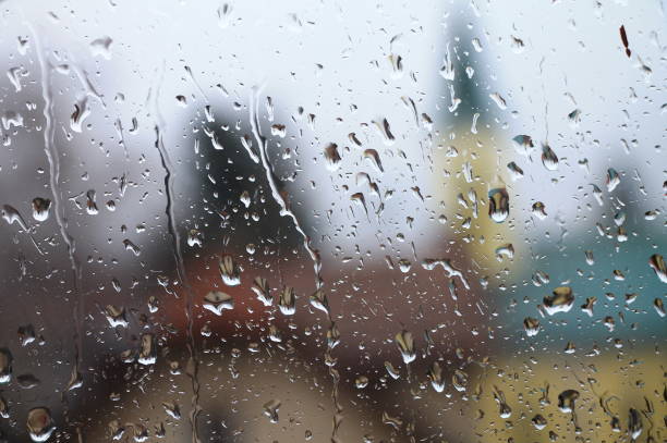 istock Rain drops on window with house and church in background 657567940