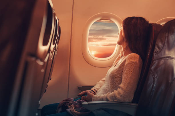 Young woman flying to France Woman in airplane looking through the window commercial airplane stock pictures, royalty-free photos & images