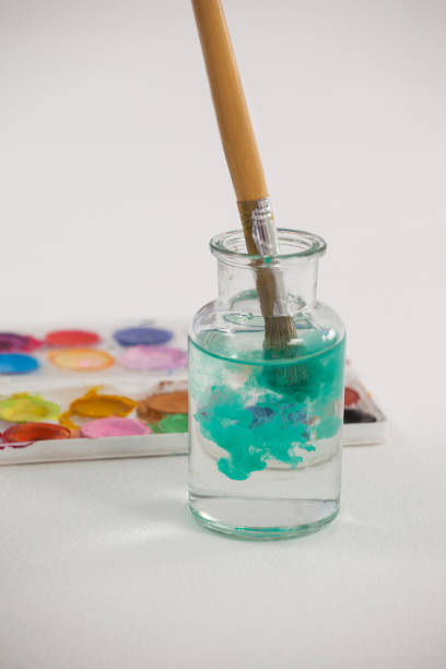 istock Paintbrush with blue paint dipped into a jar filled with water 657596530