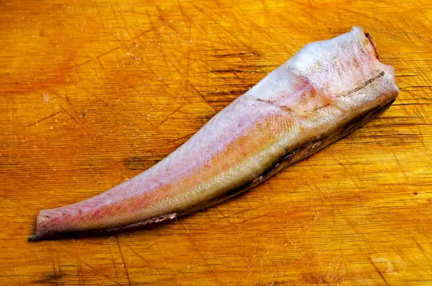 Raw fish on a cutting board for cooking."n