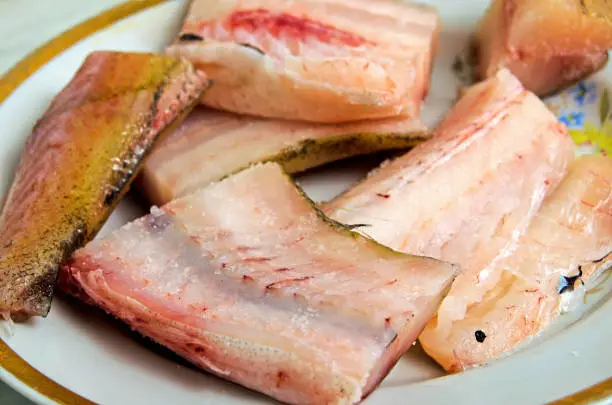 Chunks of raw fish on a plate close-up.