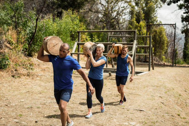 People carrying heavy wooden logs during obstacle course in boot camp