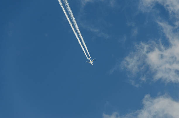 istock Airplane with reaction trail flying over blue sky with clouds, close up 657606732
