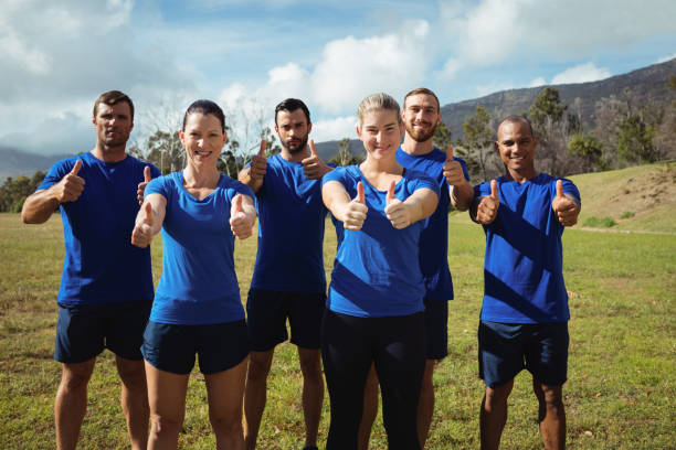 gruppo di persone che mostrano i pollici in su durante l'allenamento del boot camp - exercising outdoors group of people military training camp foto e immagini stock