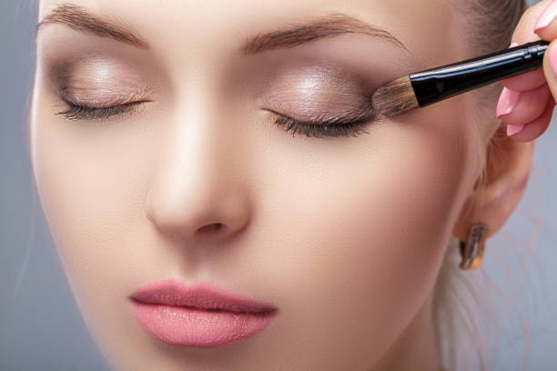 istock beautiful woman applying brown eye shadow using makeup brush. makeup for blue eyes 657630450