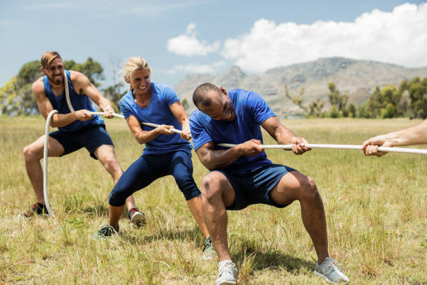 persone che giocano a tiro alla guerra durante il corso di addestramento ad ostacoli - tug o war foto e immagini stock