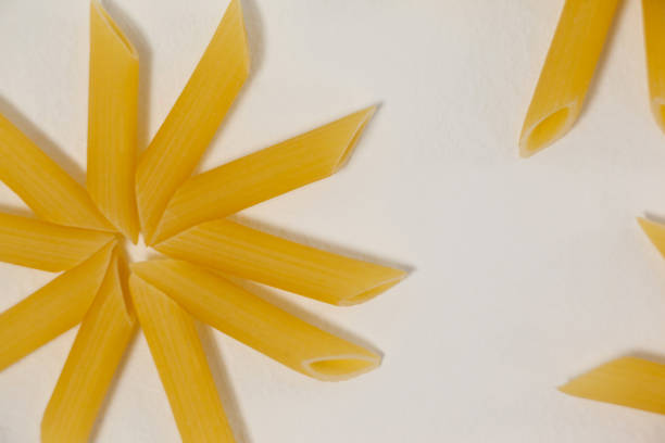 Flowers formed of pennette pasta on white background