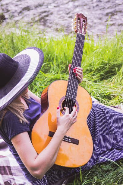 istock young woman sitting on a field and playing guitar 657650722