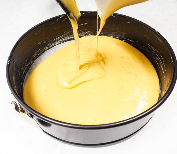 Baker adding cake mixture into a black cake ring stock photo