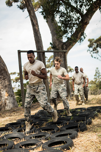Young military soldiers practicing tyre obstacle course at boot camp
