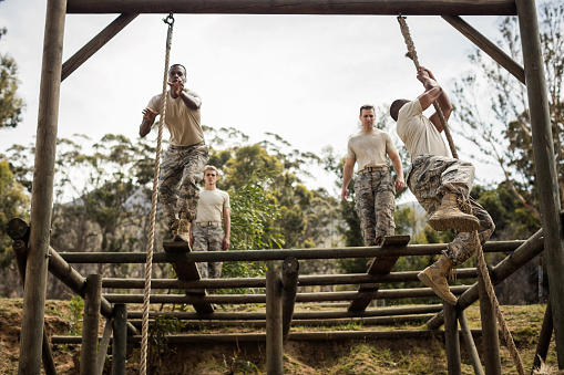 Military soldiers training rope climbing at boot camp